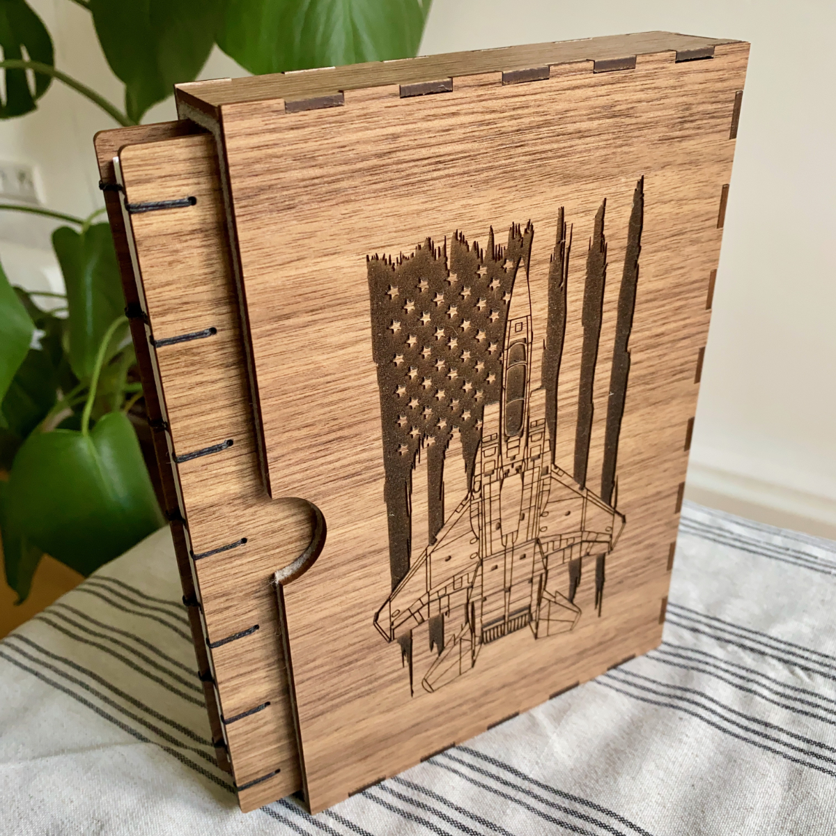 A retirement Fondfolio and slipcase for a US Air Force pilot. Walnut wooden covers, coptic bound, the book is pictured in its slip case engraved with a Fighter Jet with an American flag behind it.